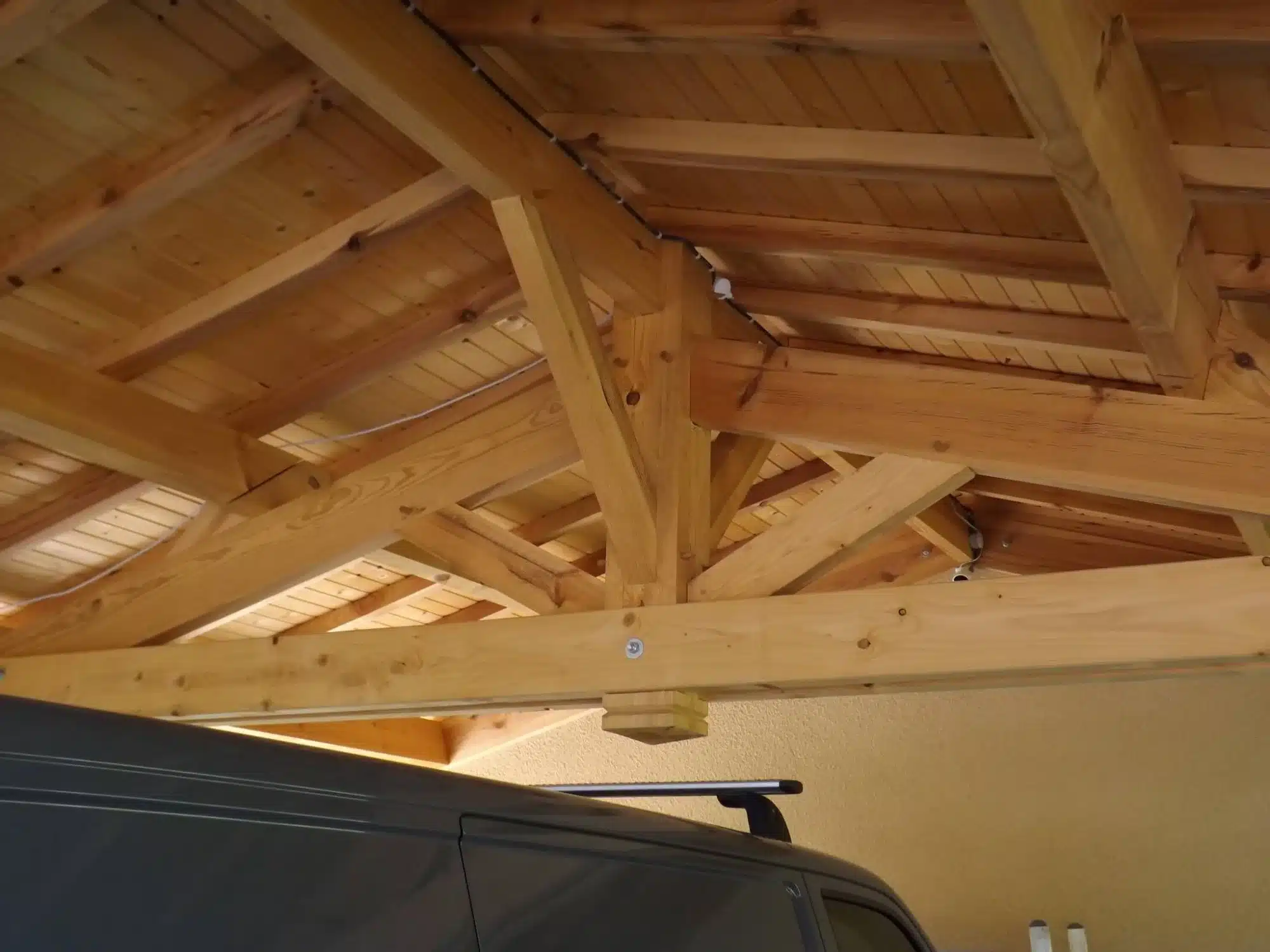 Charpente bois traditionnelle : Structure et ossature de toiture Charpente bois neuve symétrique. Ossature de toiture en poutres et chevrons s'élevant vers la faîtière, fond de ciel nuageux.