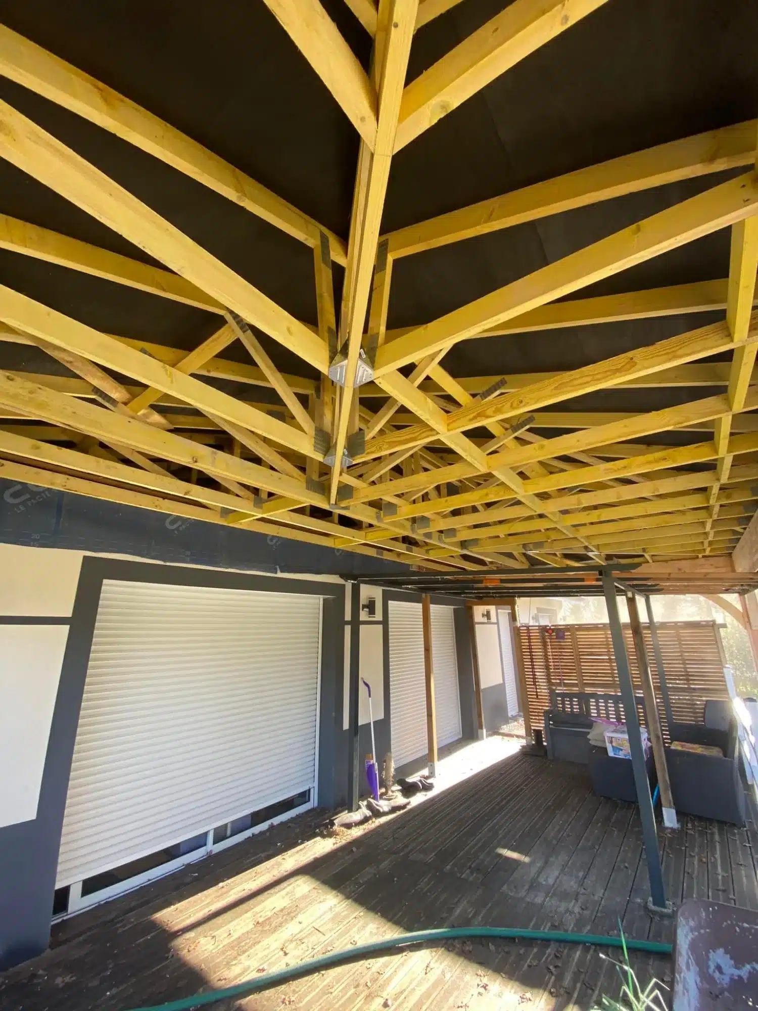 Charpente bois traditionnelle : Structure et ossature de toiture Charpente bois neuve symétrique. Ossature de toiture en poutres et chevrons s'élevant vers la faîtière, fond de ciel nuageux.