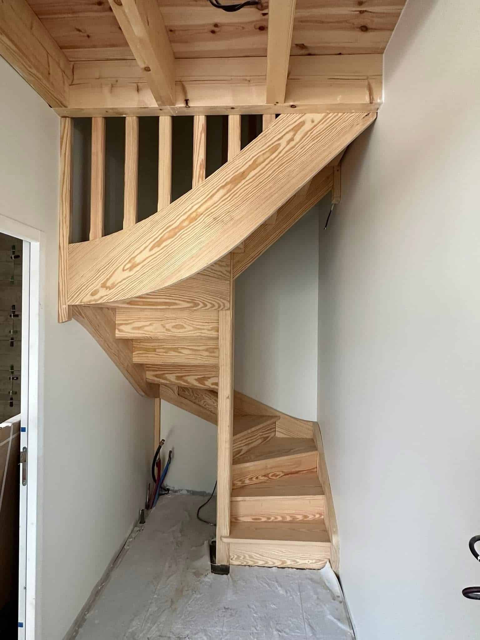 Escalier en Colimaçon en Bois Massif Design Moderne Escalier tournant en bois clair installé dans un hall étroit, structure artisanale avec rampe intégrée.