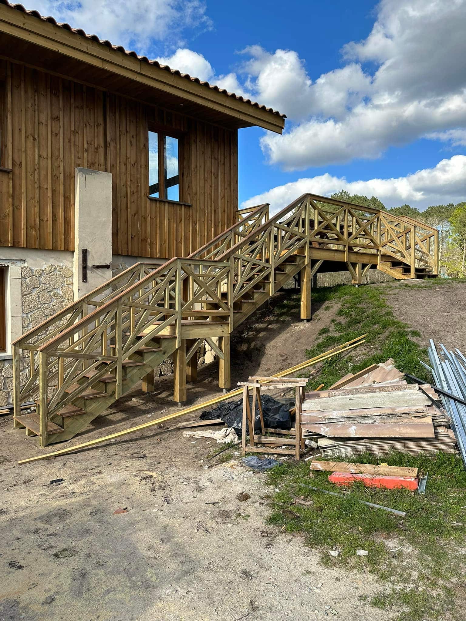Charpente bois traditionnelle : Structure et ossature de toiture Charpente bois neuve symétrique. Ossature de toiture en poutres et chevrons s'élevant vers la faîtière, fond de ciel nuageux.