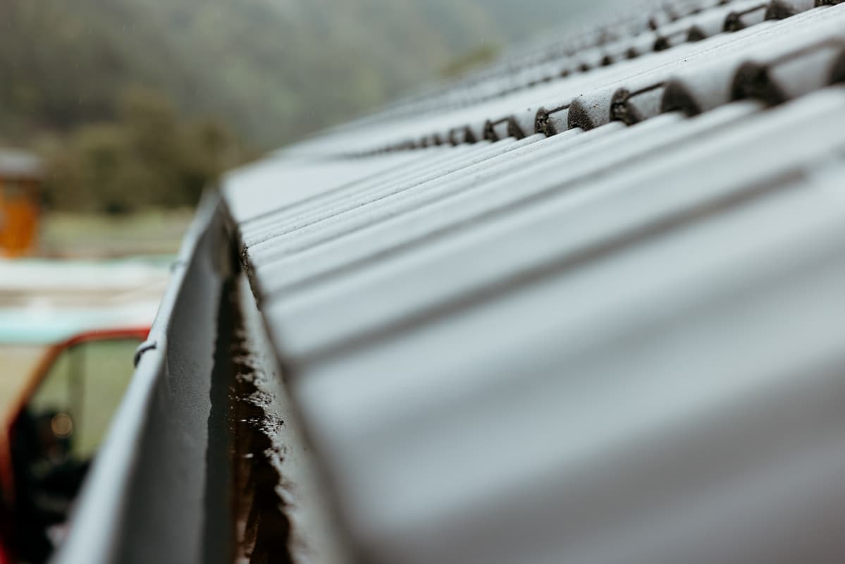 Charpente bois traditionnelle : Structure et ossature de toiture Charpente bois neuve symétrique. Ossature de toiture en poutres et chevrons s'élevant vers la faîtière, fond de ciel nuageux.