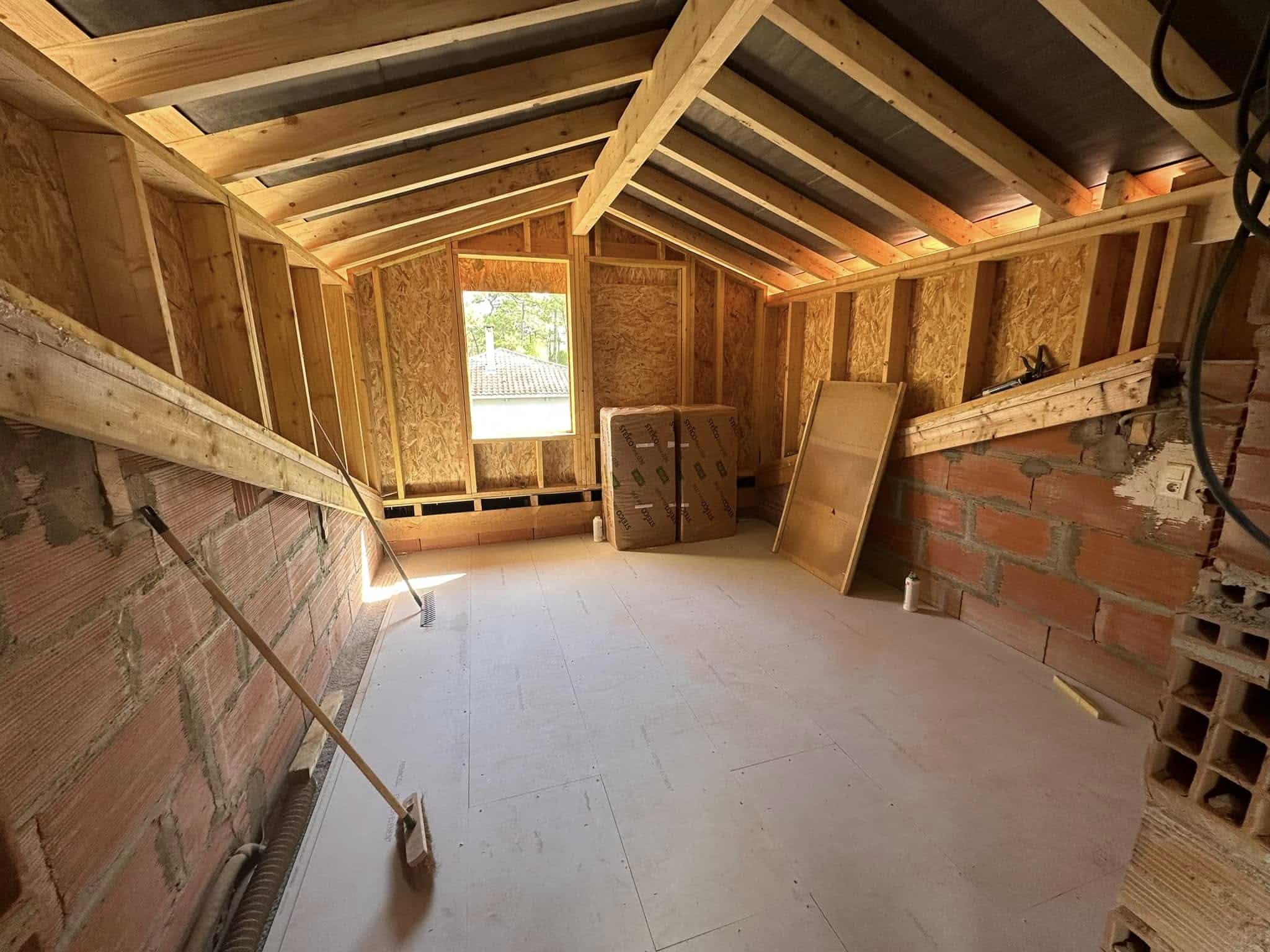 Chantier d'aménagement de combles avec charpente bois, murs en briques et isolant Steico.