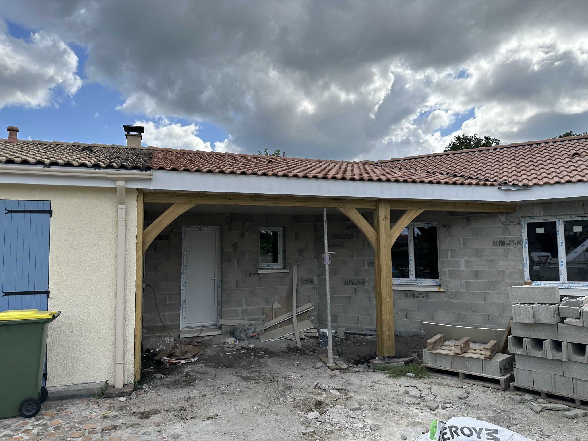 Chantier d'extension en bois et parpaings sous toit en tuiles.